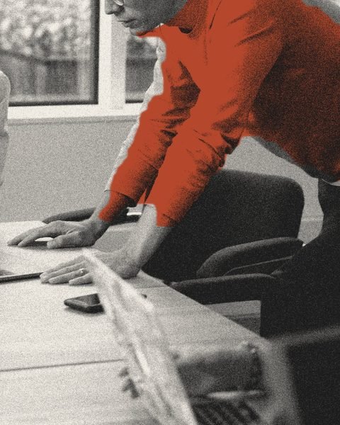 Deux personnes penchées ensemble sur une table de travail, devant un ordinateur.